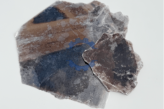 A piece of rock featuring a blue and white logo, identified as Muscovite (Ruby) Mica.